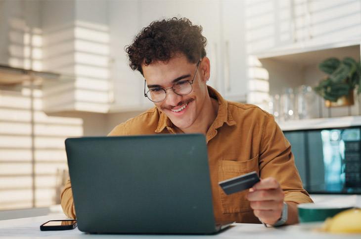 Smiling Man at computer holding credit card